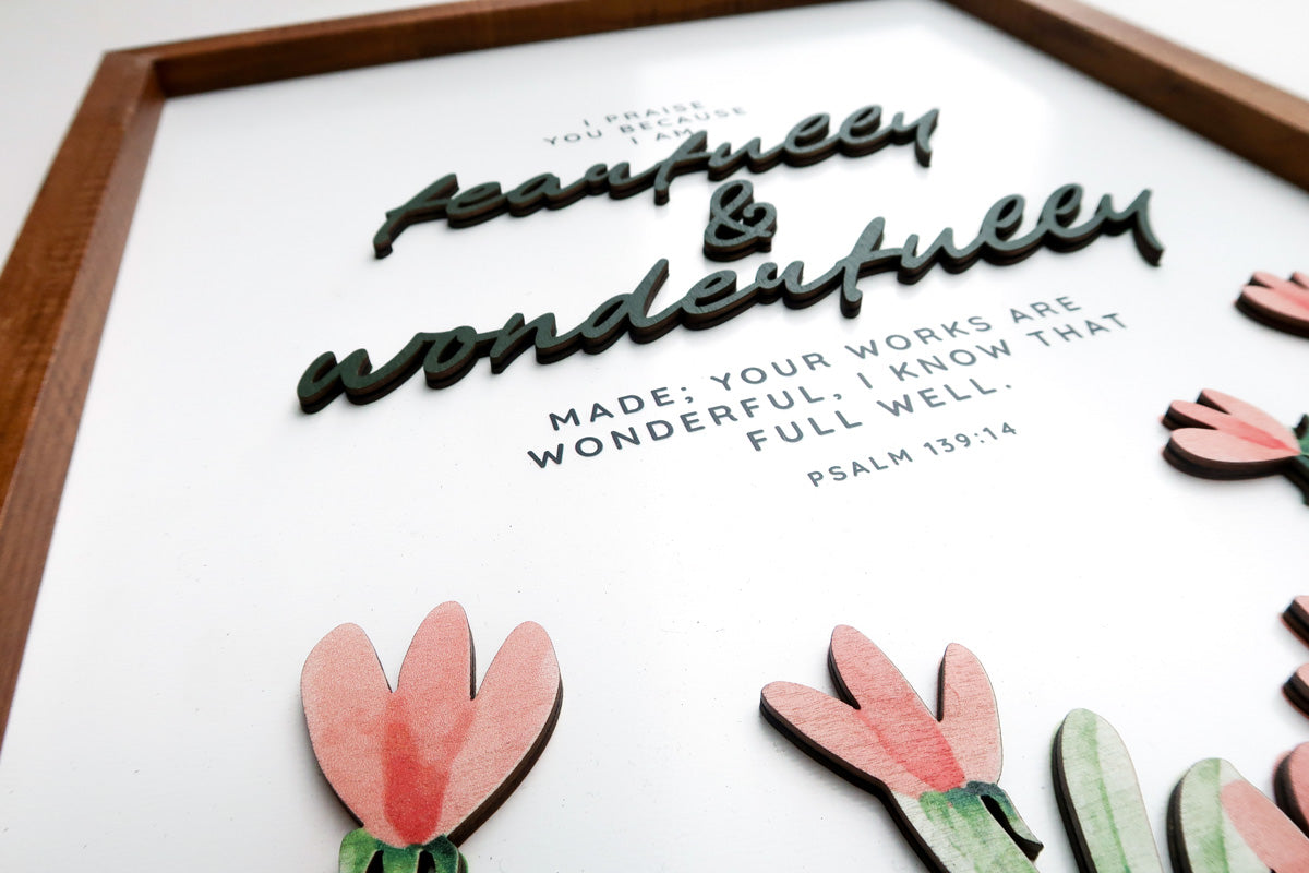 Close-up view of a wooden scripture poster featuring the Bible verse Psalm 139:14, "Fearfully and wonderfully made," with layered 3D text and delicate floral accents.