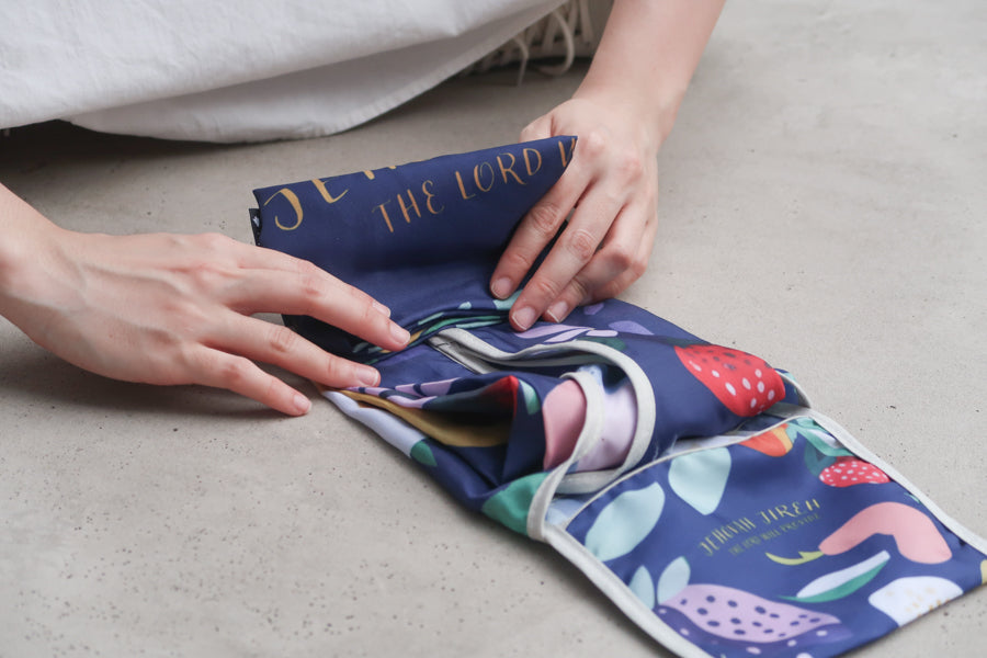 Hands folding a reusable
Bible verse shopping bag
with fruit design, showing
its compact and practical
nature for Christian gifts
from a Christian gift store.