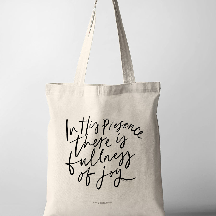 Beige tote bag with the words 'In His presence there is fullness of joy' from Psalm 16:11 printed in black handwritten-style script on the front.