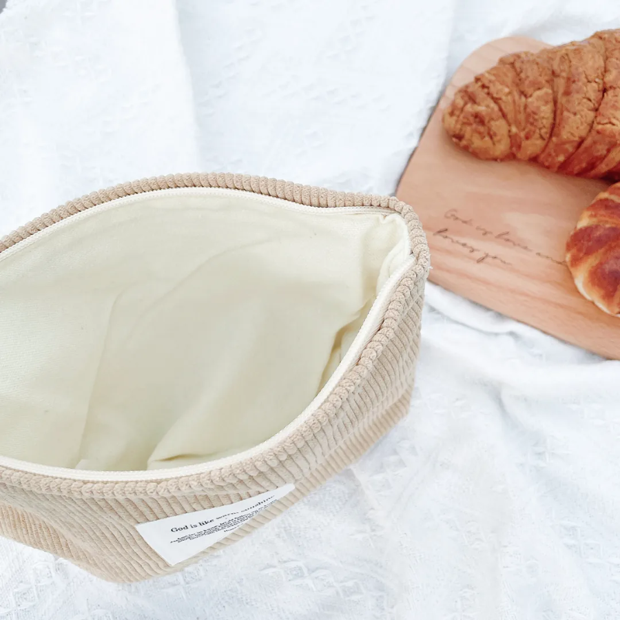 God is like warm sunshine beige corduroy zipper clutch with an inspirational message patch, placed on a textured white fabric, radiating simple happiness and encouragement.