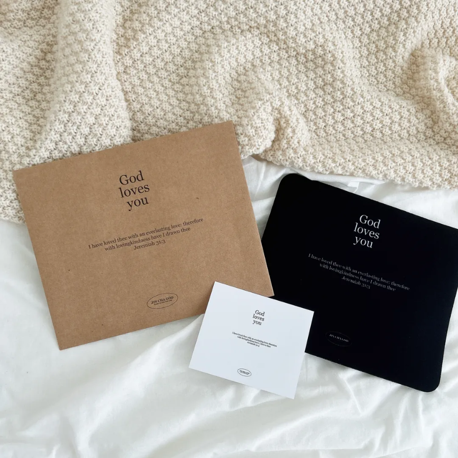 "God loves you" mouse pad, card, and packaging with Jeremiah 31:3, displayed on a cozy cream blanket, offering daily Christian encouragement and simple happiness