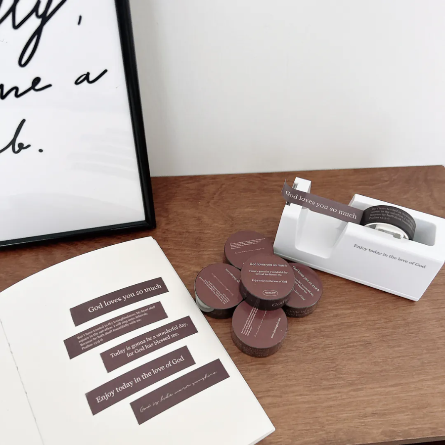 Brown Christian washi tape set with encouraging messages like "God loves you so much," displayed with a tape dispenser and journal, perfect for faith-inspired journaling and sharing simple happiness.