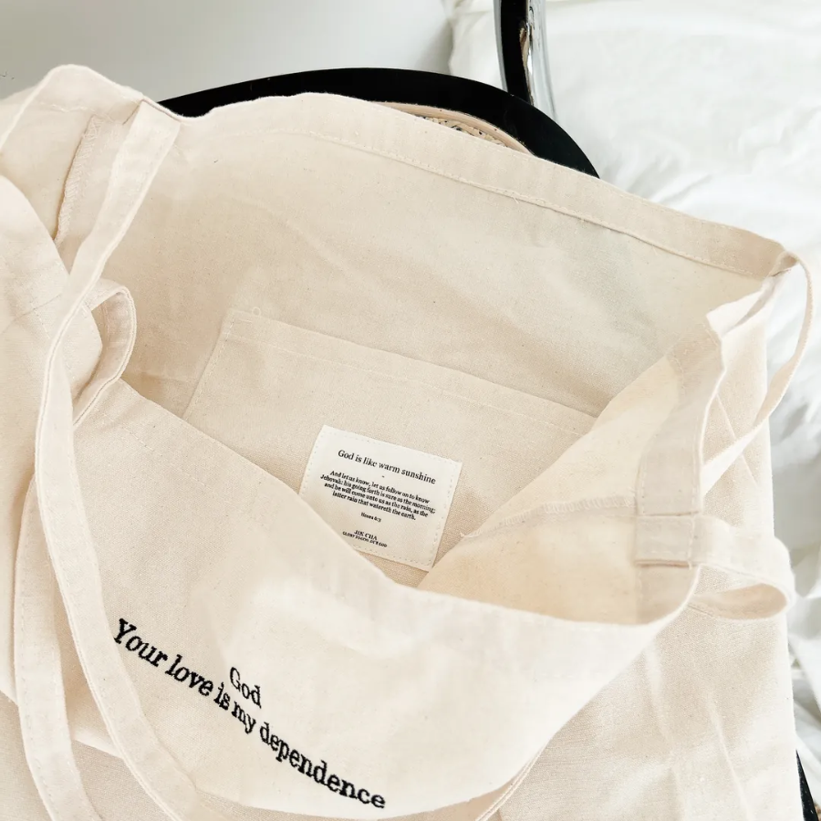God Your love is my dependence canvas tote bag in cream, showing the inspirational inner pocket label "God is like warm sunshine," reflecting faith, encouragement, and simple happiness.