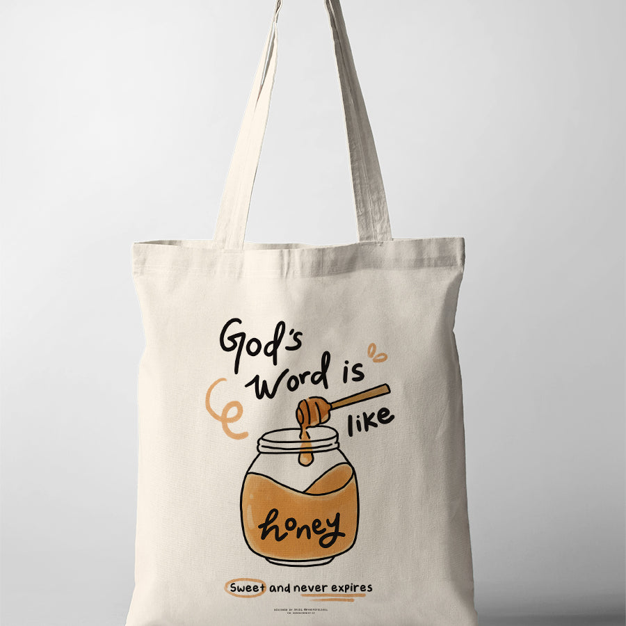 Cream canvas tote bag featuring “God’s Word is like honey – Sweet and never expires” with illustrated honey jar and dipper design, Christian inspirational tote bag.