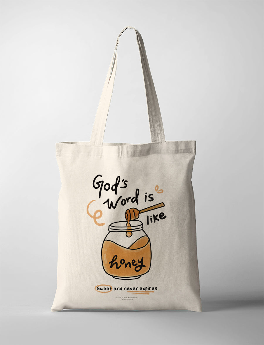 Cream canvas tote bag featuring “God’s Word is like honey – Sweet and never expires” with illustrated honey jar and dipper design, Christian inspirational tote bag.