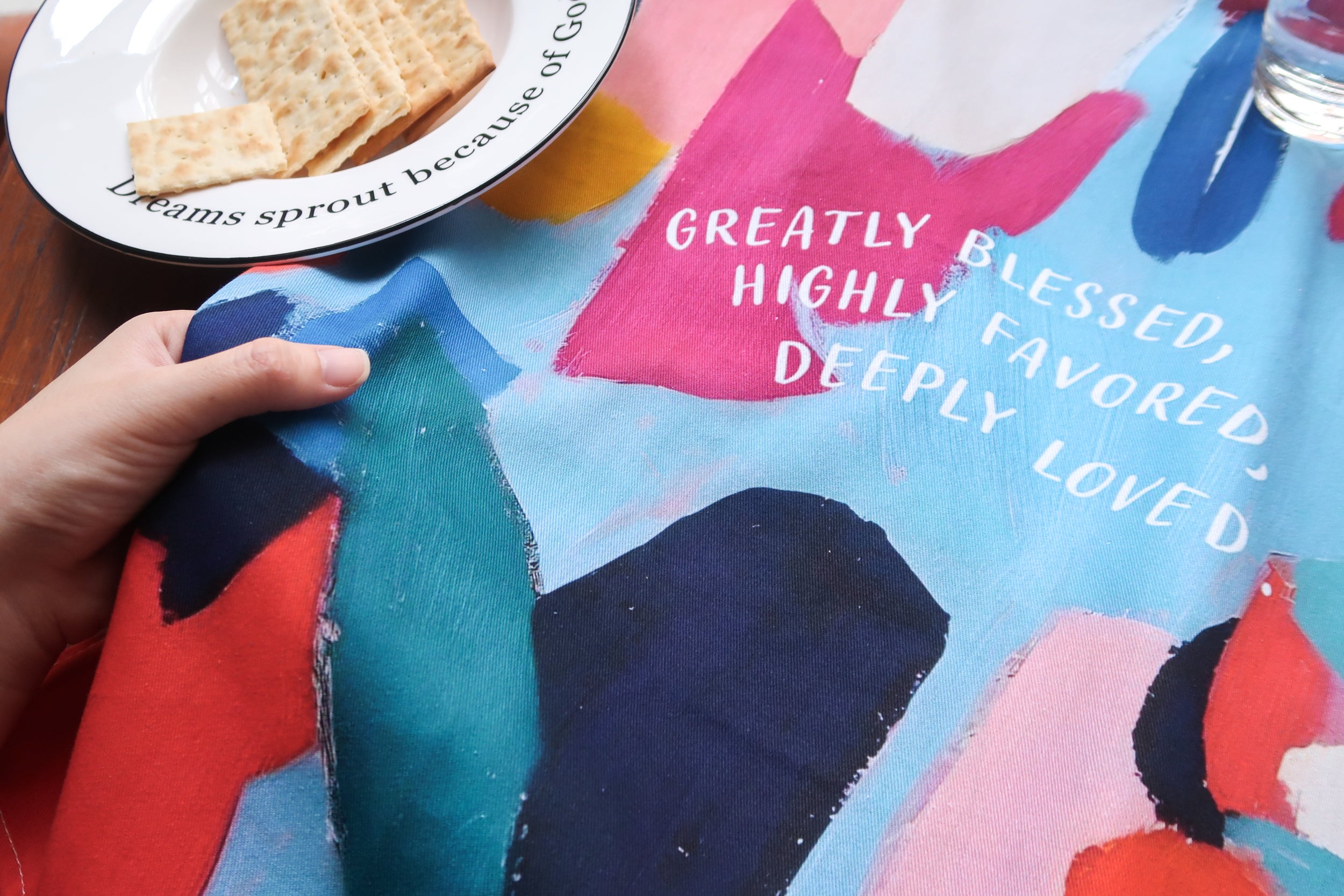 Greatly Blessed Tea Towel with colorful abstract artwork and the uplifting phrase “Greatly Blessed, Highly Favored, Deeply Loved”—a faith-based kitchen decor item from The Commandment Co.