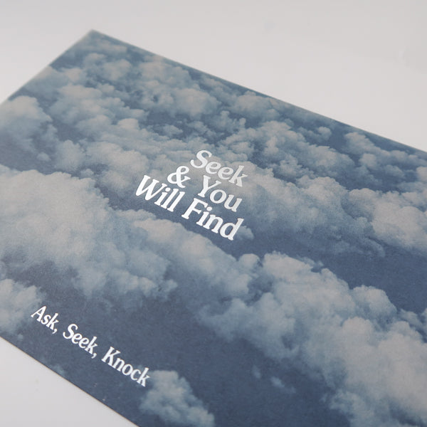 A detailed view of a postcard showing a serene sky filled with clouds and the uplifting message "Seek & You Will Find" with the additional text "Ask, Seek, Knock," encouraging hope and perseverance.