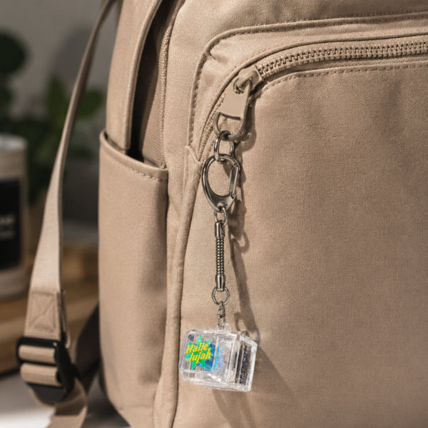 Hallelujah light-up keycap keychain clipped to a beige backpack