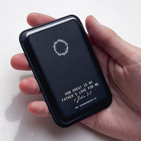 A hand holding a Black Leather Magsafe Wallet