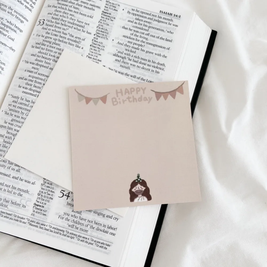 "Happy Birthday" postcard with bunting and a cute illustration of Jesus in a party hat, placed on an open Bible, offering encouragement and joy for special occasions.