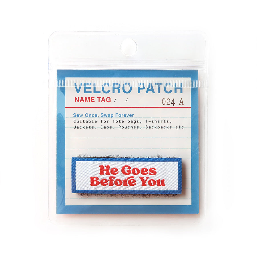 Velcro tag with 'He Goes Before You' text in red on a white and blue background, a Christian inspirational patch for bags and apparel.
