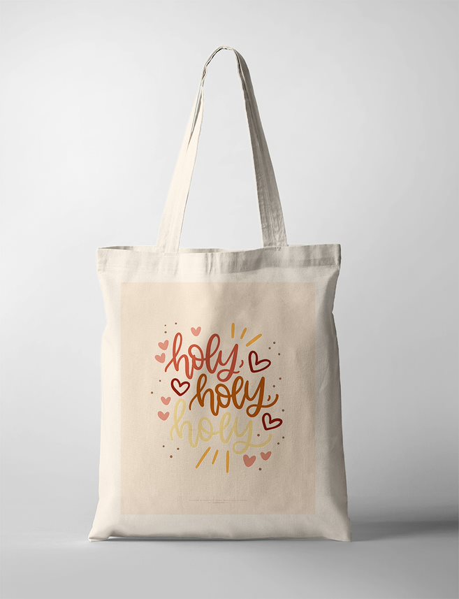 A faith-based Tote Bag featuring the words 'Holy, Holy, Holy' in warm, earthy typography with red and gold hand-drawn hearts and decorative dots. The minimalist Christian wall art has a soft beige background, framed in a simple wooden frame, making it a perfect decor piece for a faith-inspired home or prayer space.