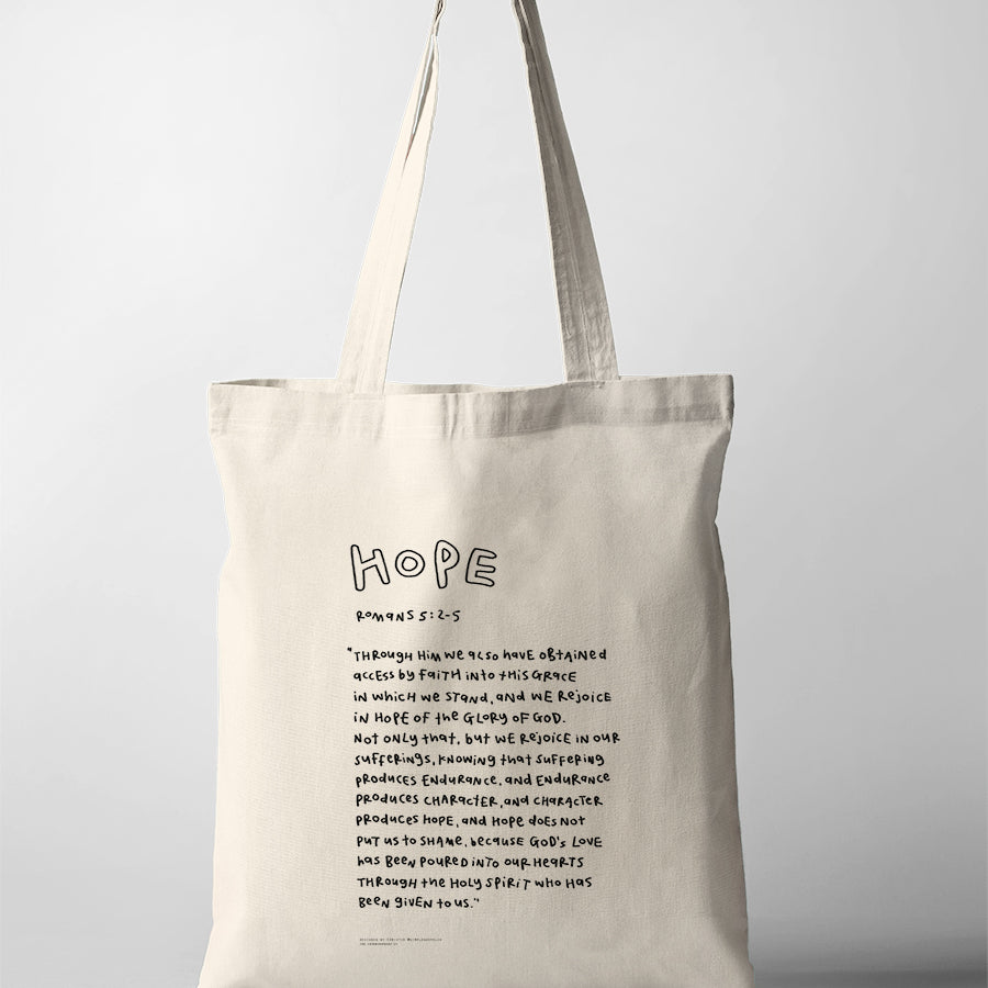 Hope Bible verse tote bag featuring Romans 5:2-5 in a handwritten typography design on a natural canvas tote.
