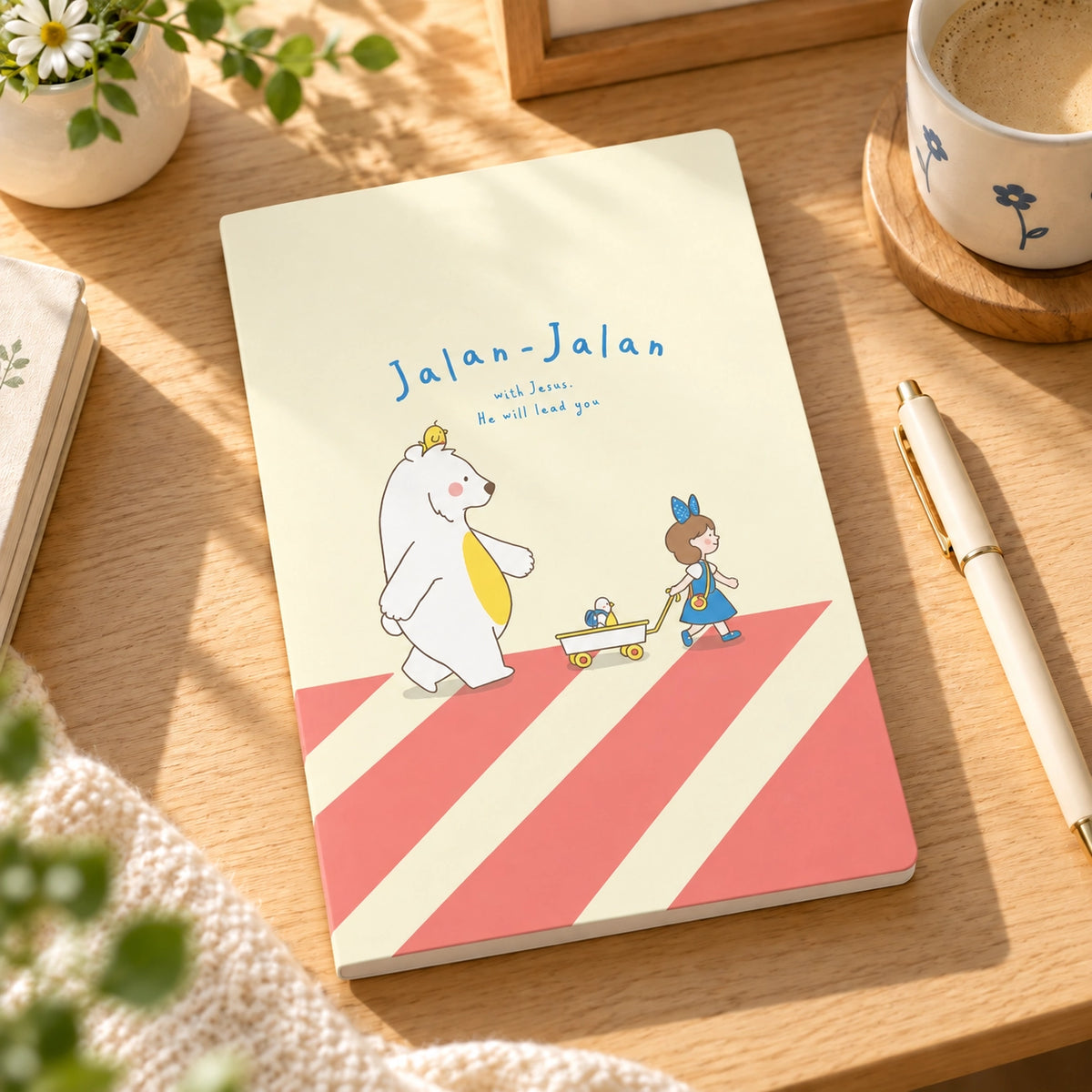 Jalan-Jalan With Jesus A5 Christian notebook styled on a warm sunlit desk with stationery.
