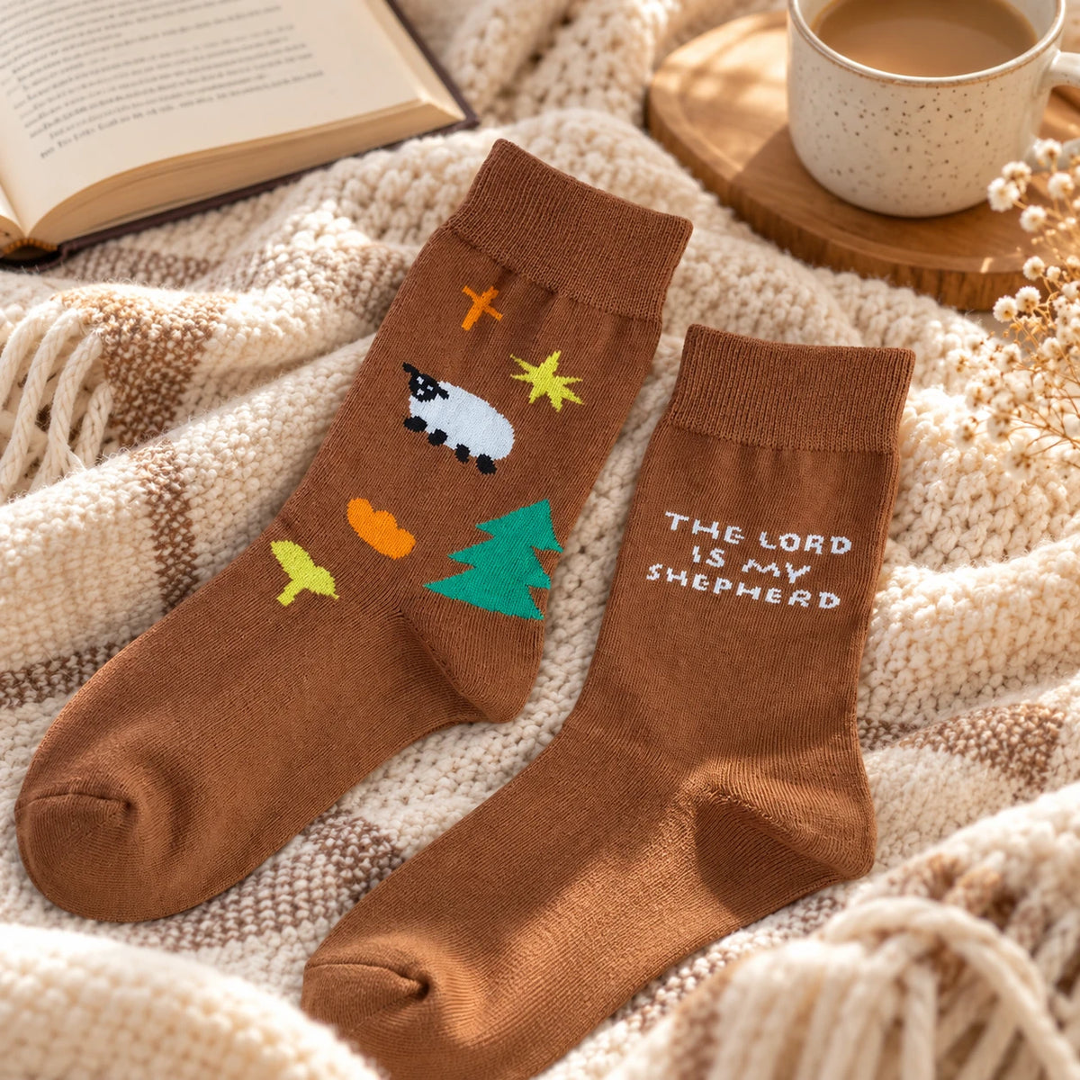 Jesus Is My Shepherd I Lack Nothing brown Christian socks styled on a cosy blanket beside a book and coffee.