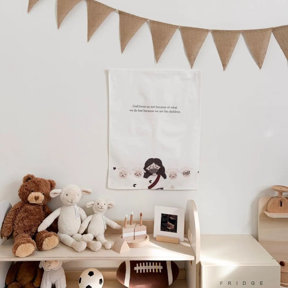 Christian cotton linen wall hanging with “God loves us not because of what we do but because we are His children” displayed in a children’s room