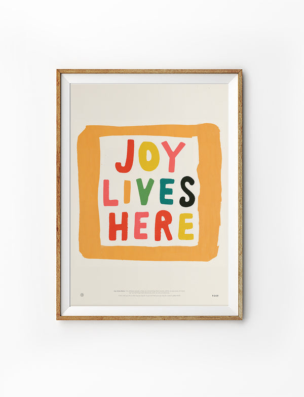 Colourful Joy Lives Here Christian poster in a light wood frame