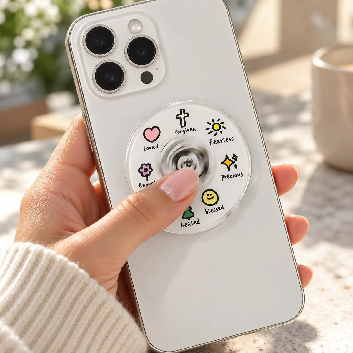 Jesus spinner phone grip featuring faith icons on a white phone held in a hand.