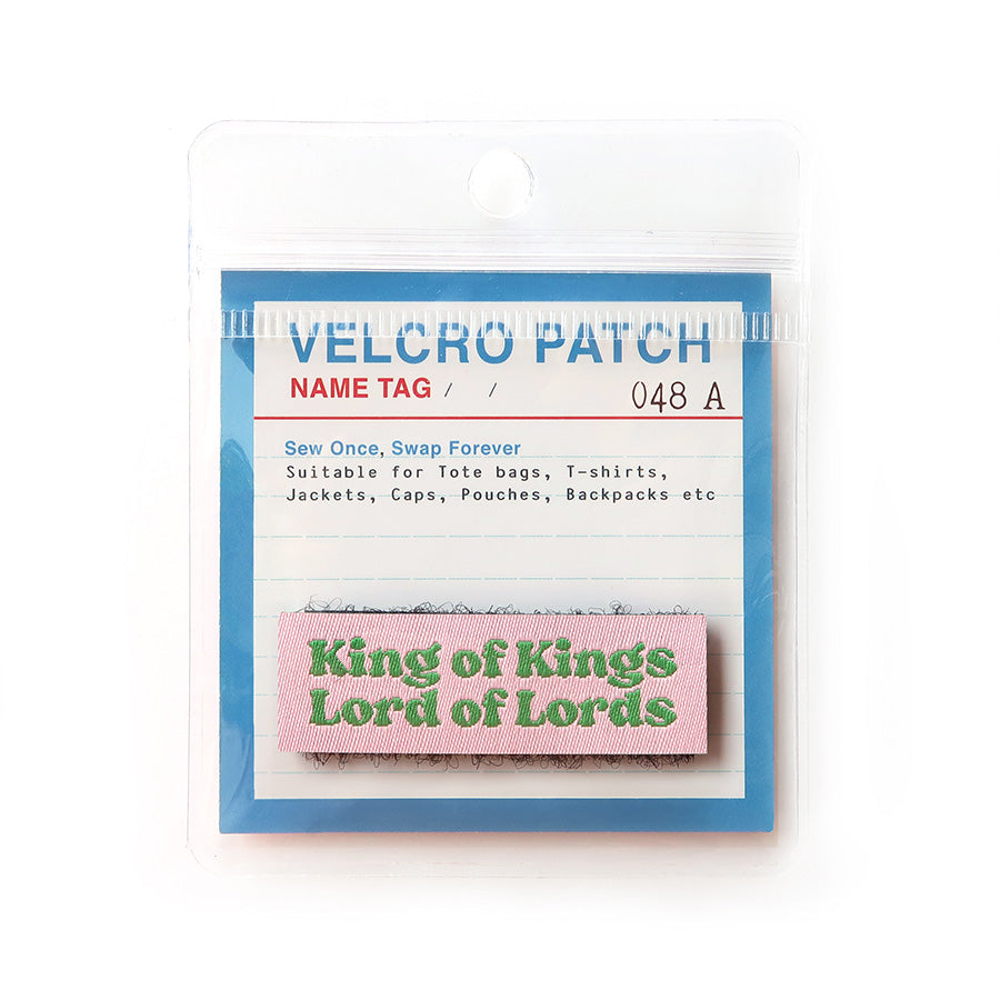 Pink Velcro tag with green text 'King of Kings, Lord of Lords,' an inspirational Christian embroidered patch for clothing and accessories.