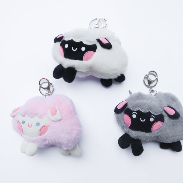 Three faith-inspired Lil Sheepies plush keychains in White Cumulus, Pink Hana, and Stormy Gray are displayed on a white background. Each soft, fluffy sheep represents a reminder of the Good Shepherd’s love, featuring a Bible verse charm, a retractable string for easy card access, and a secure keychain clip. Perfect as a Christian gift or daily faith companion.
