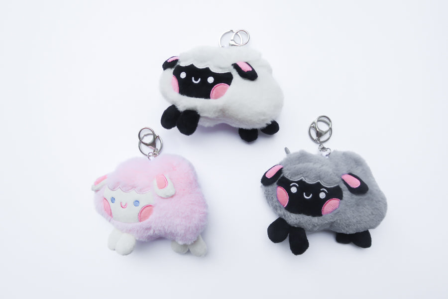 Three faith-inspired Lil Sheepies plush keychains in White Cumulus, Pink Hana, and Stormy Gray are displayed on a white background. Each soft, fluffy sheep represents a reminder of the Good Shepherd’s love, featuring a Bible verse charm, a retractable string for easy card access, and a secure keychain clip. Perfect as a Christian gift or daily faith companion.