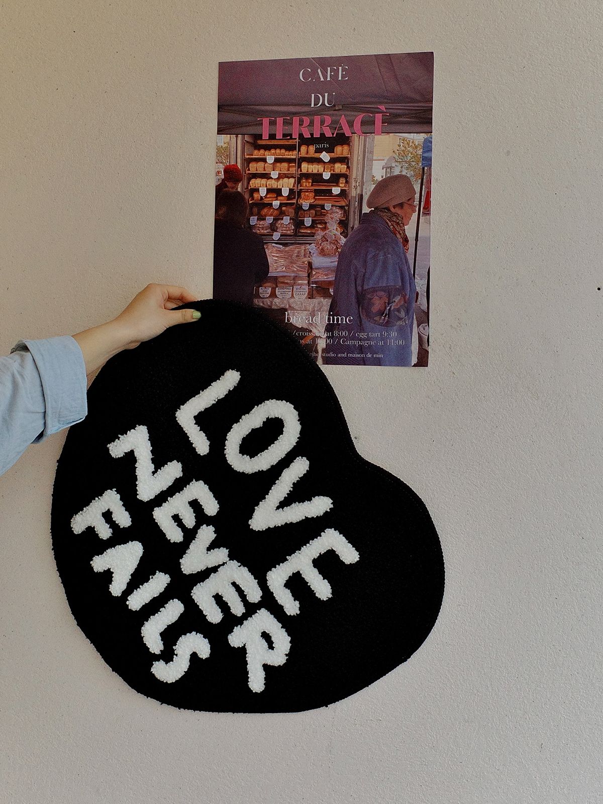 Lifestyle photo of a Love Never Fails heart-shaped tufted rug held against a wall, suitable as a Christian gift.