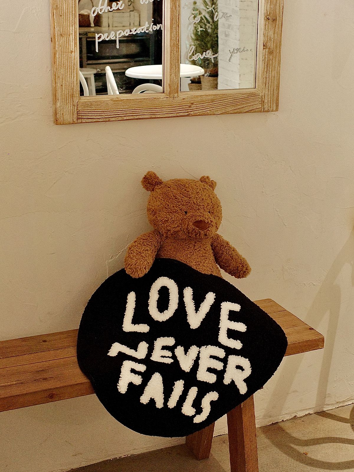 Love Never Fails heart rug styled indoors with a wooden bench and teddy bear for a cozy home decor look.