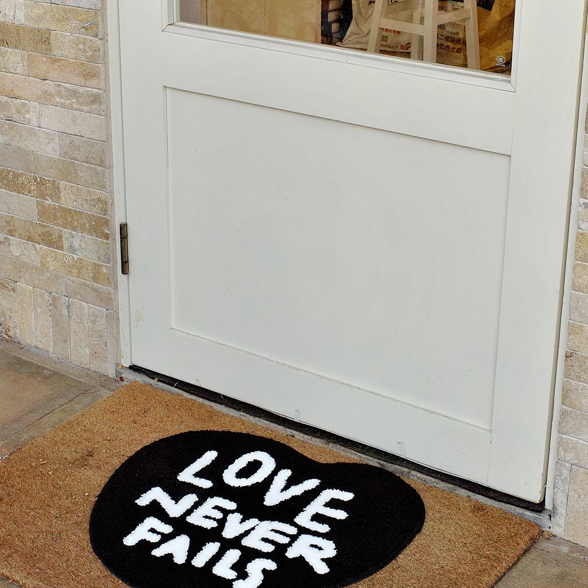 Love Never Fails heart rug placed at an entryway in front of a white door as a faith-inspired welcome mat.