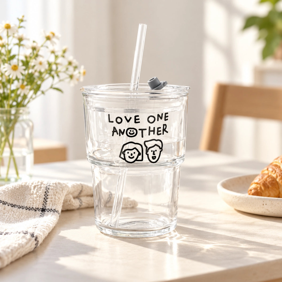 Love One Another glass tumbler with reusable straw styled on a bright homely table with flowers and breakfast