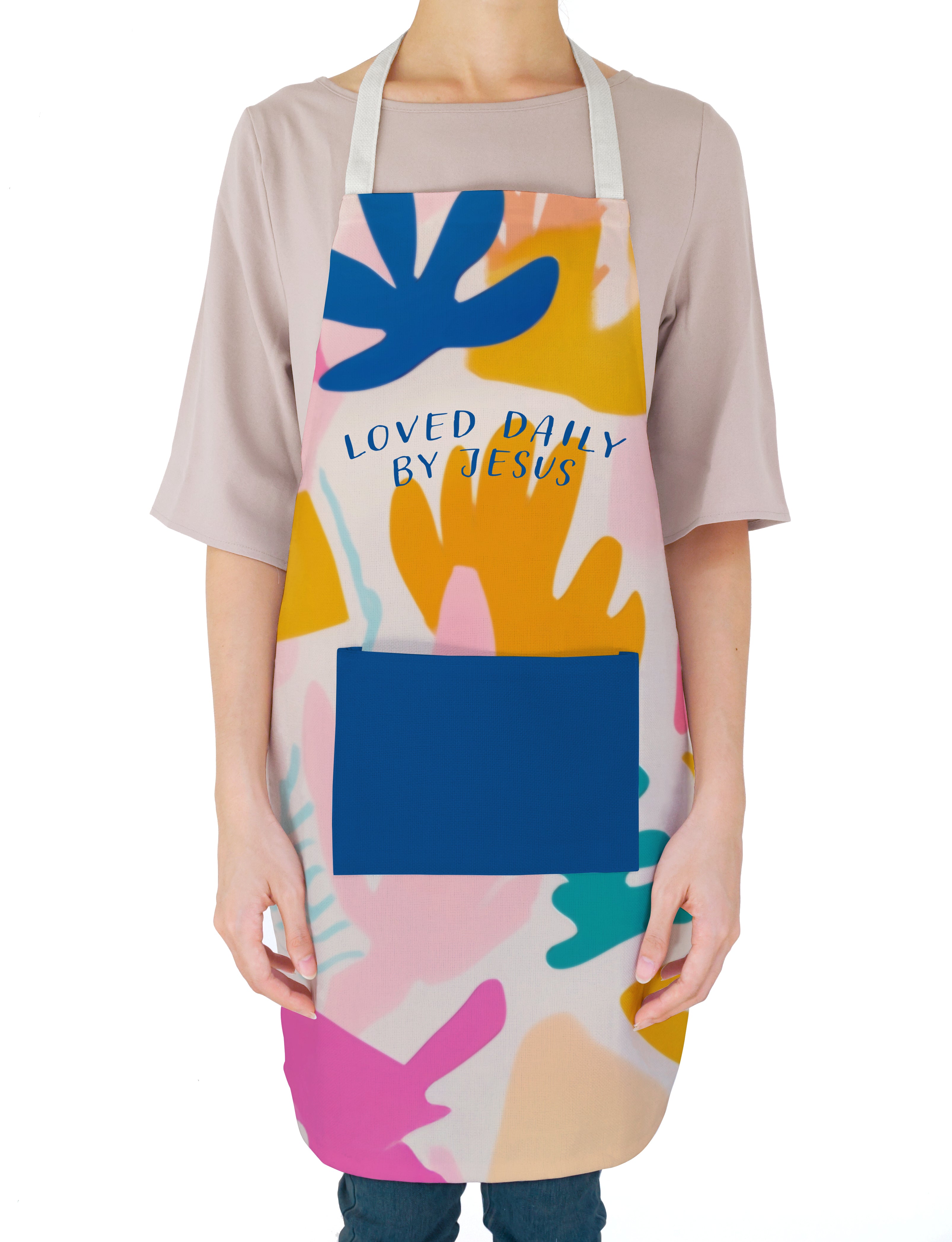 A person wearing a vibrant "Loved Daily by Jesus" apron with abstract, colorful shapes, spreading encouragement, faith, and the joy of simple happiness in everyday life.