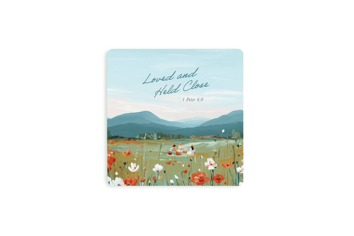 Christian coaster with “Loved and Held Close” and 1 Peter 4:8 featuring a peaceful floral field scene with mountains and soft pastel sky