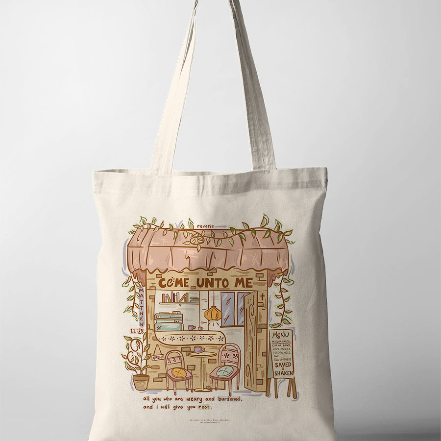 Canvas Christian tote bag featuring cozy café illustration with the verse “Come unto me all who are weary and I will give you rest” from Matthew 11:28