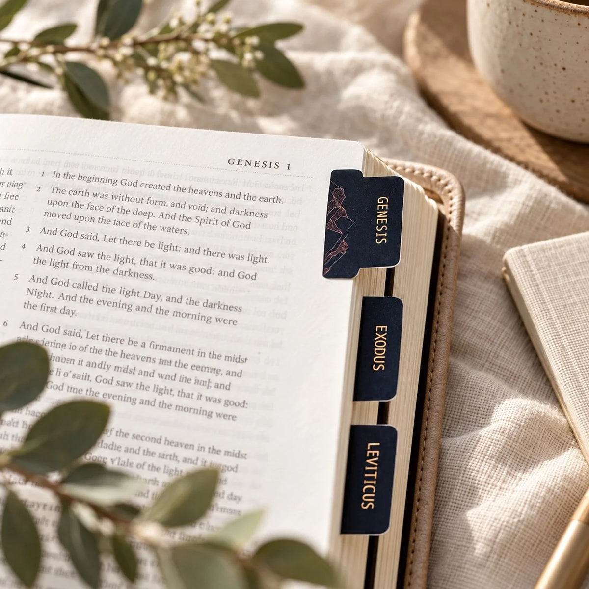 Midnight Wonder navy black and gold book of the Bible tabs visible on an open Bible at Genesis 1