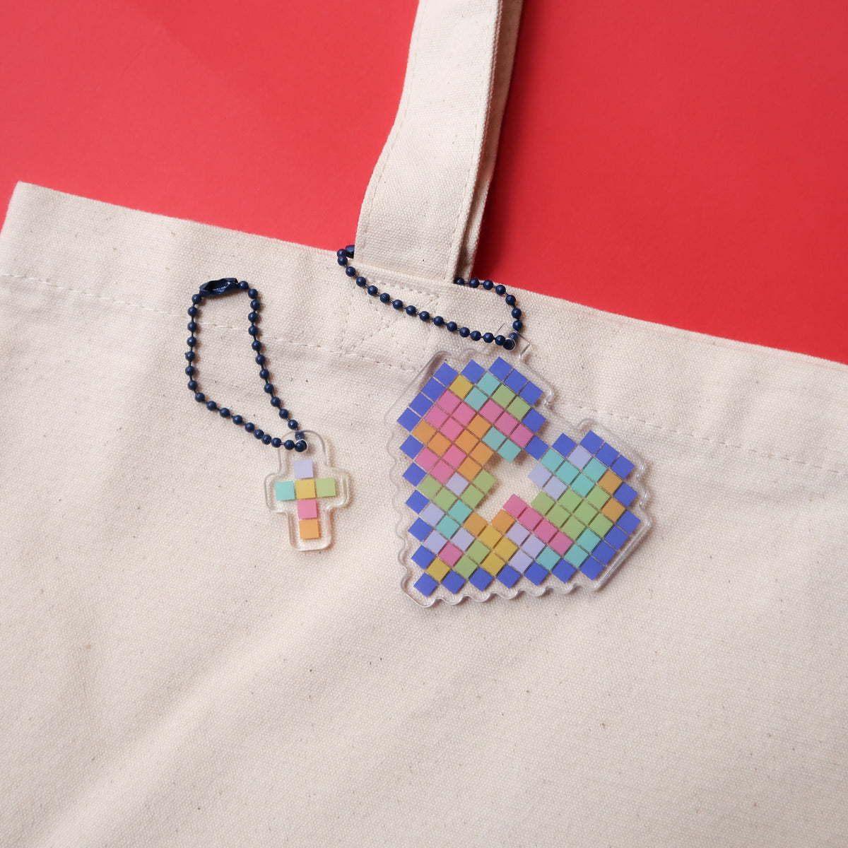 Mosaic heart and cross acrylic keychains attached to a tote bag, from The Commandment Co, Singapore.