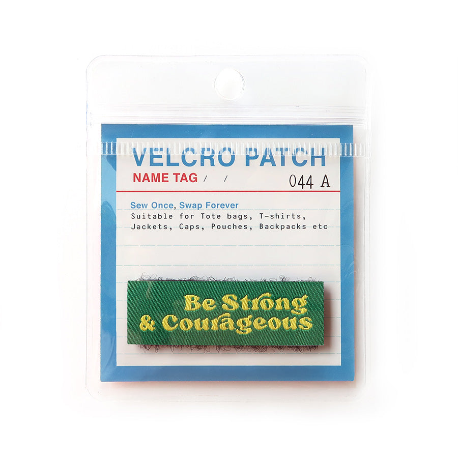 Green Velcro tag with yellow text 'Be Strong & Courageous,' an inspirational embroidered patch for faith-based apparel and accessories