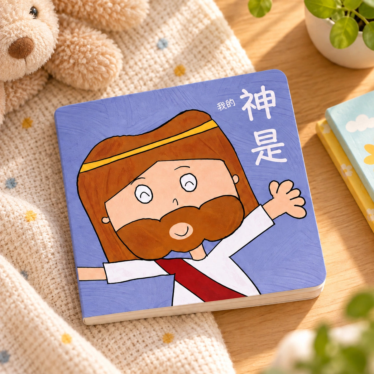 My God Is Chinese children's storybook lying flat on a warm wooden table beside soft nursery decor.