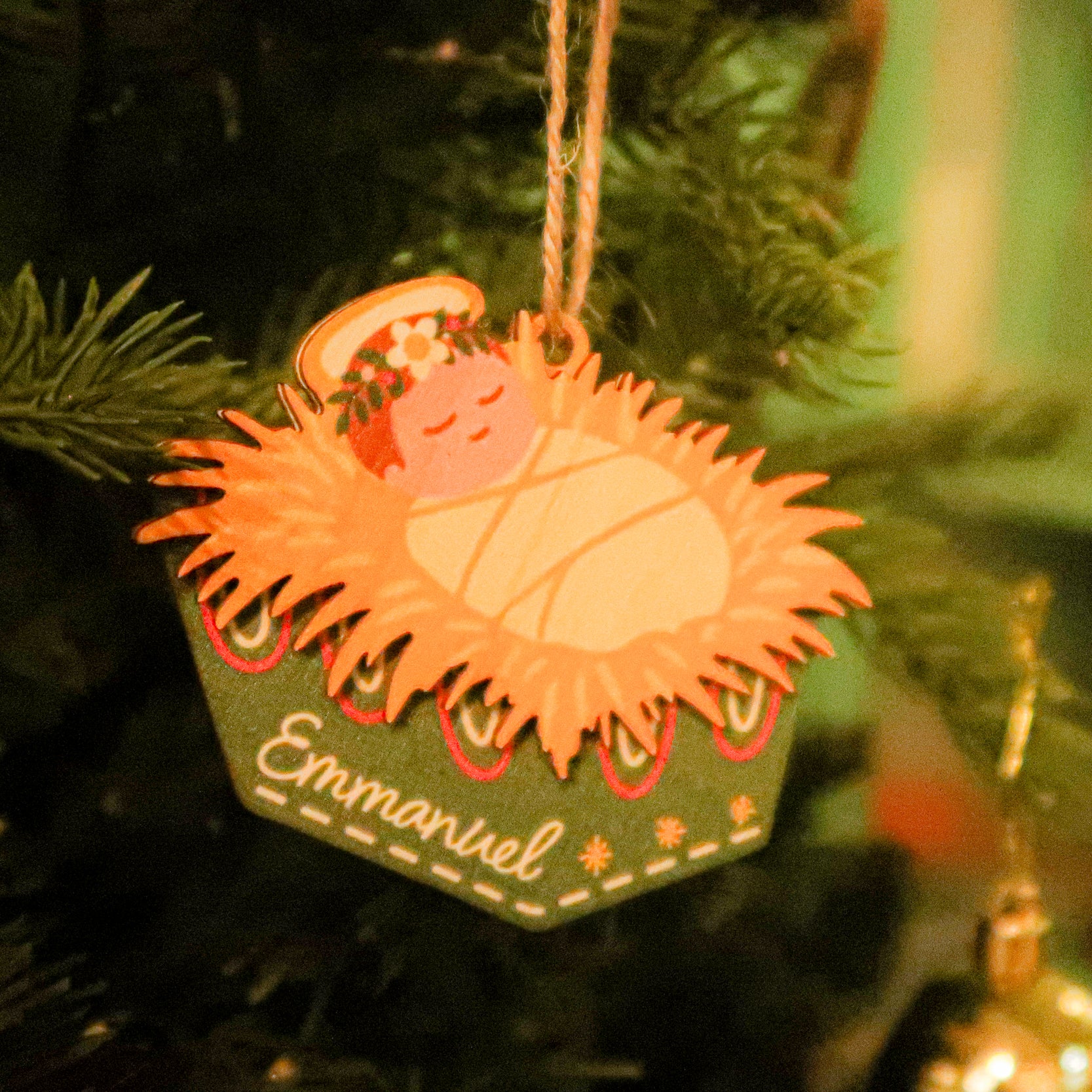 Emmanuel baby Jesus Christmas bauble hanging on a decorated Christmas tree