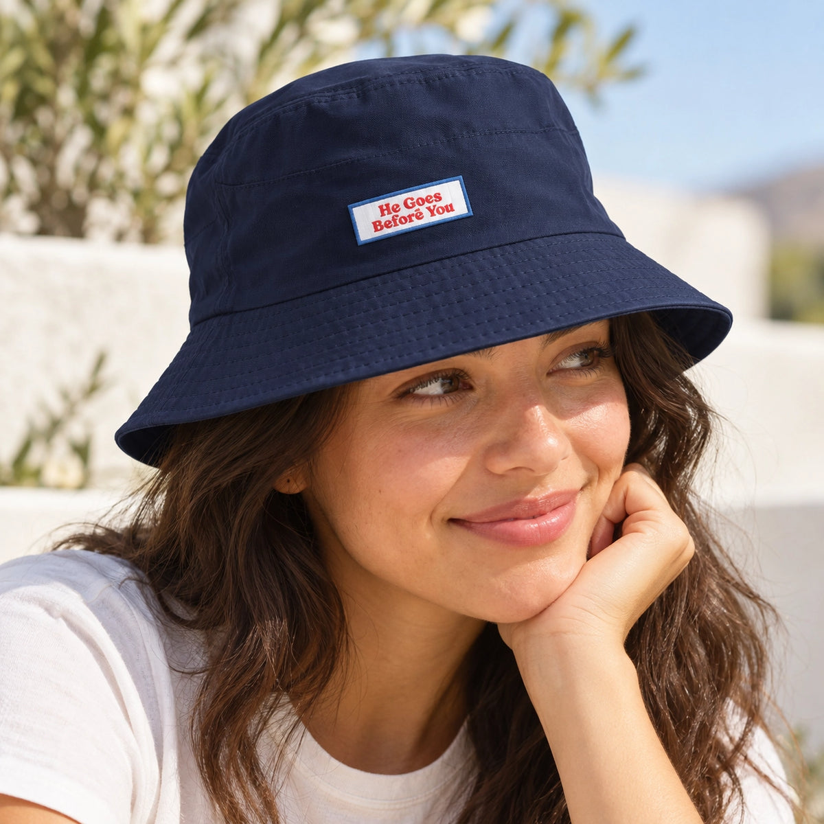 Woman wearing the navy blue bucket hat with He Goes Before You Velcro patch outdoors.