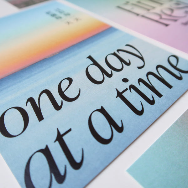 A thoughtfully crafted postcard featuring the uplifting message "One Day at a Time," perfect for spreading positive encouragement and daily motivation.