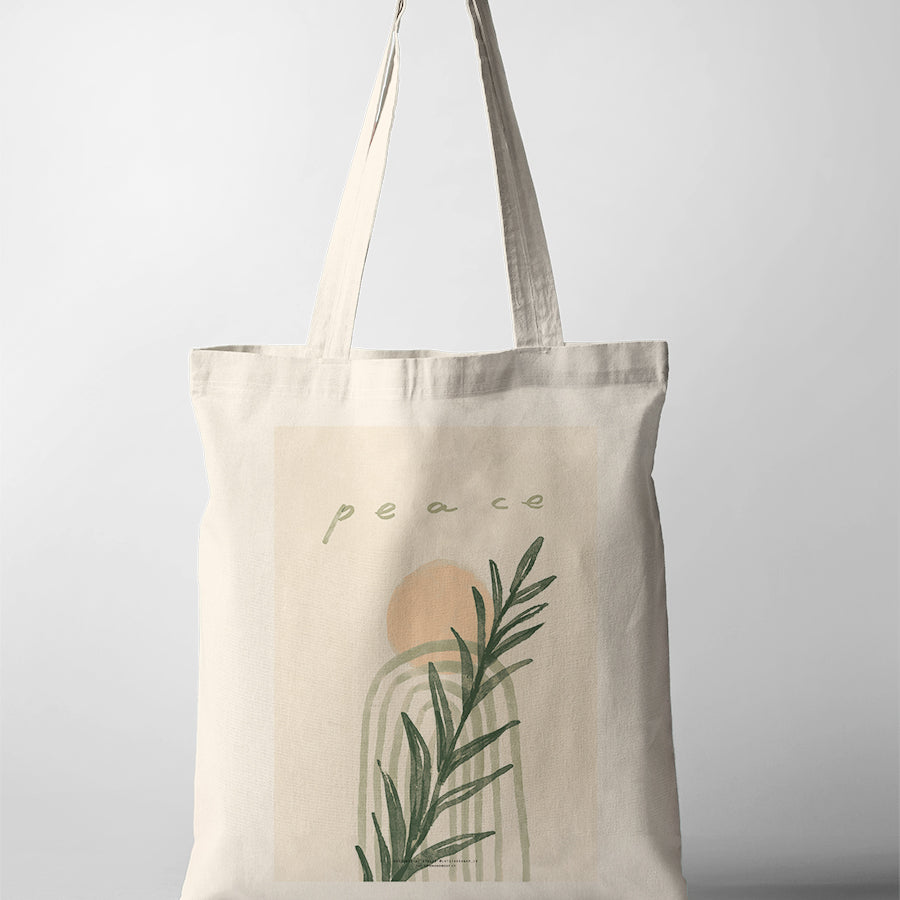 Minimalist Christian tote bag featuring the word “Peace” with abstract arches, soft peach sun, and green botanical leaves
