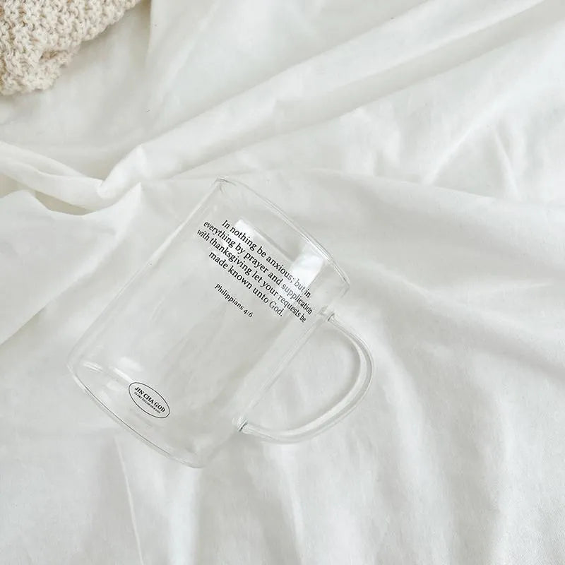 Clear Christian glass cup featuring Philippians 4:6 styled on soft white bedding for a calm and minimal everyday setting