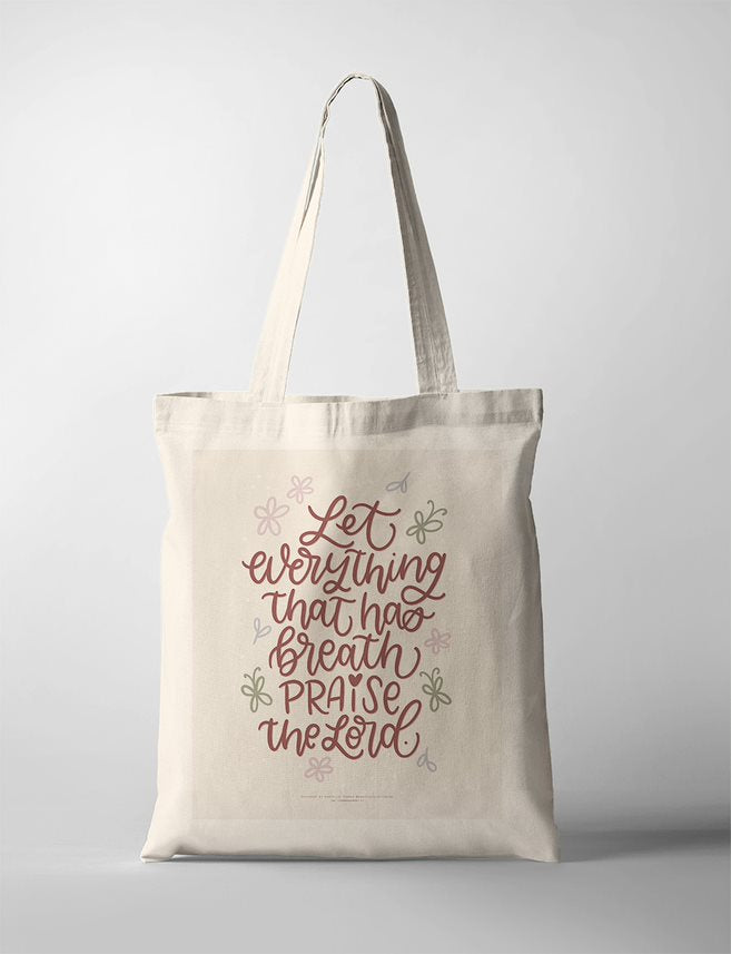 A faith-based Tote Bag featuring the Bible verse 'Let everything that has breath praise the Lord' in elegant handwritten typography. Surrounding the text are soft pastel-colored floral and leaf illustrations on a warm beige background. The Christian wall art is framed in a simple wooden frame, making it a meaningful piece for home decor, a prayer corner, or a worship space.