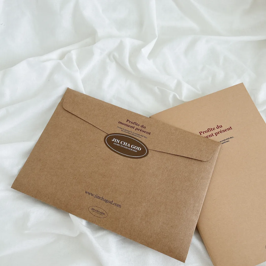 Profite du moment présent A5 notebook and matching kraft envelope with inspirational message, displayed on a soft white fabric, reflecting simple happiness and mindful living.