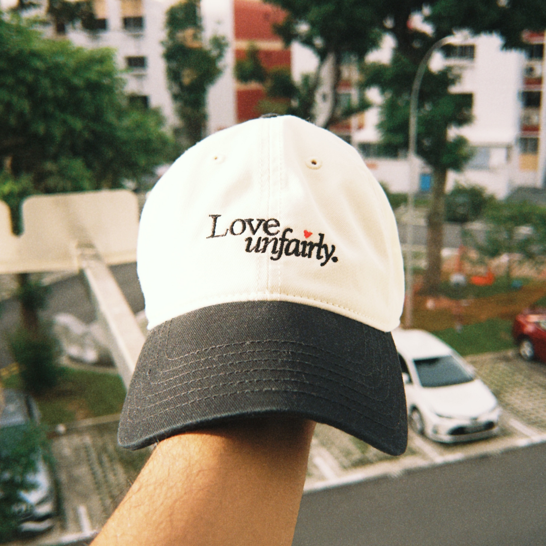 Love Unfairly cream and black cap styled outdoors