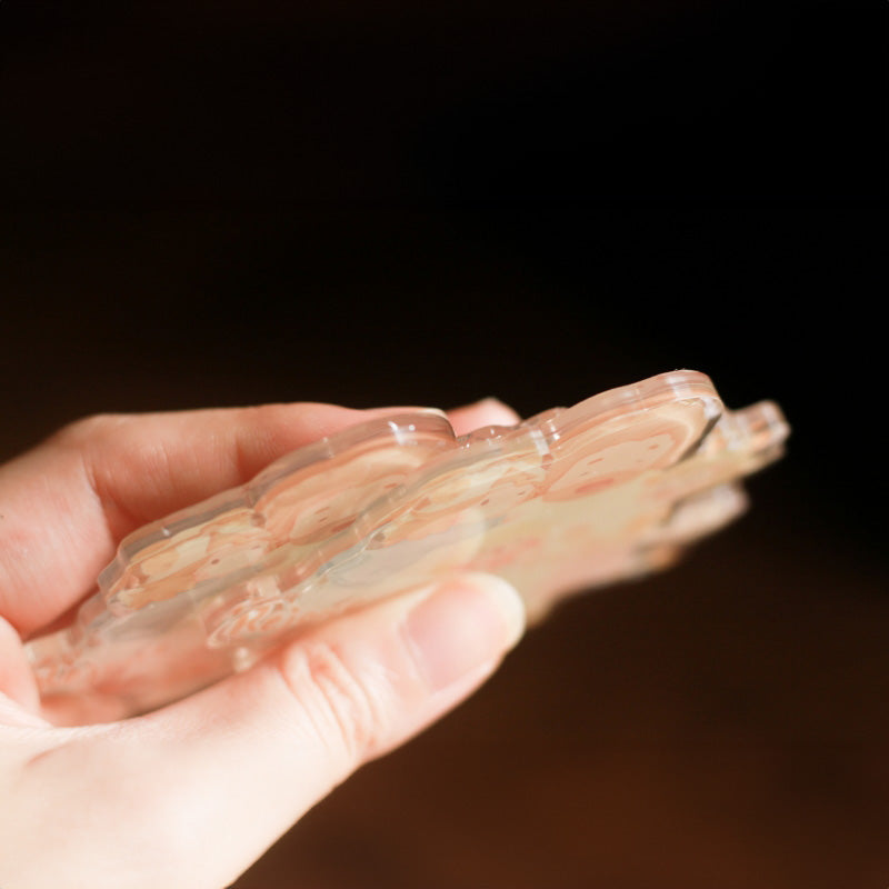 Close-Up of Decorative Magnet: "Close-up shot of a decorative magnet being held, showcasing its thickness and intricate design"