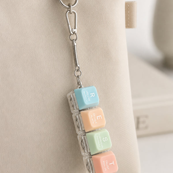 REST light-up keycap keychain clipped to a beige pouch