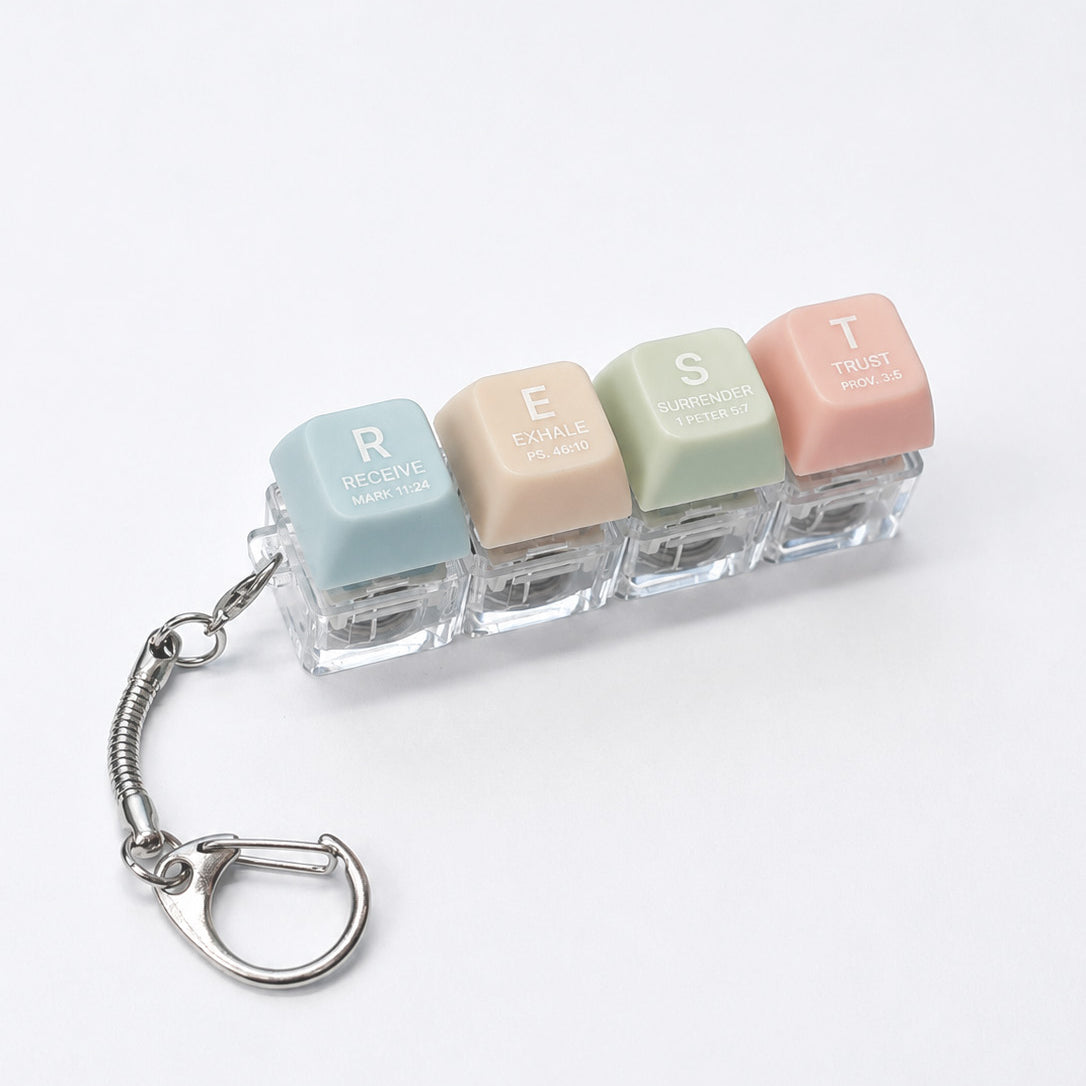 REST press-on light-up keycap keychain with pastel coloured keys spelling rest, featuring Scripture-inspired words on a bright white studio background.
