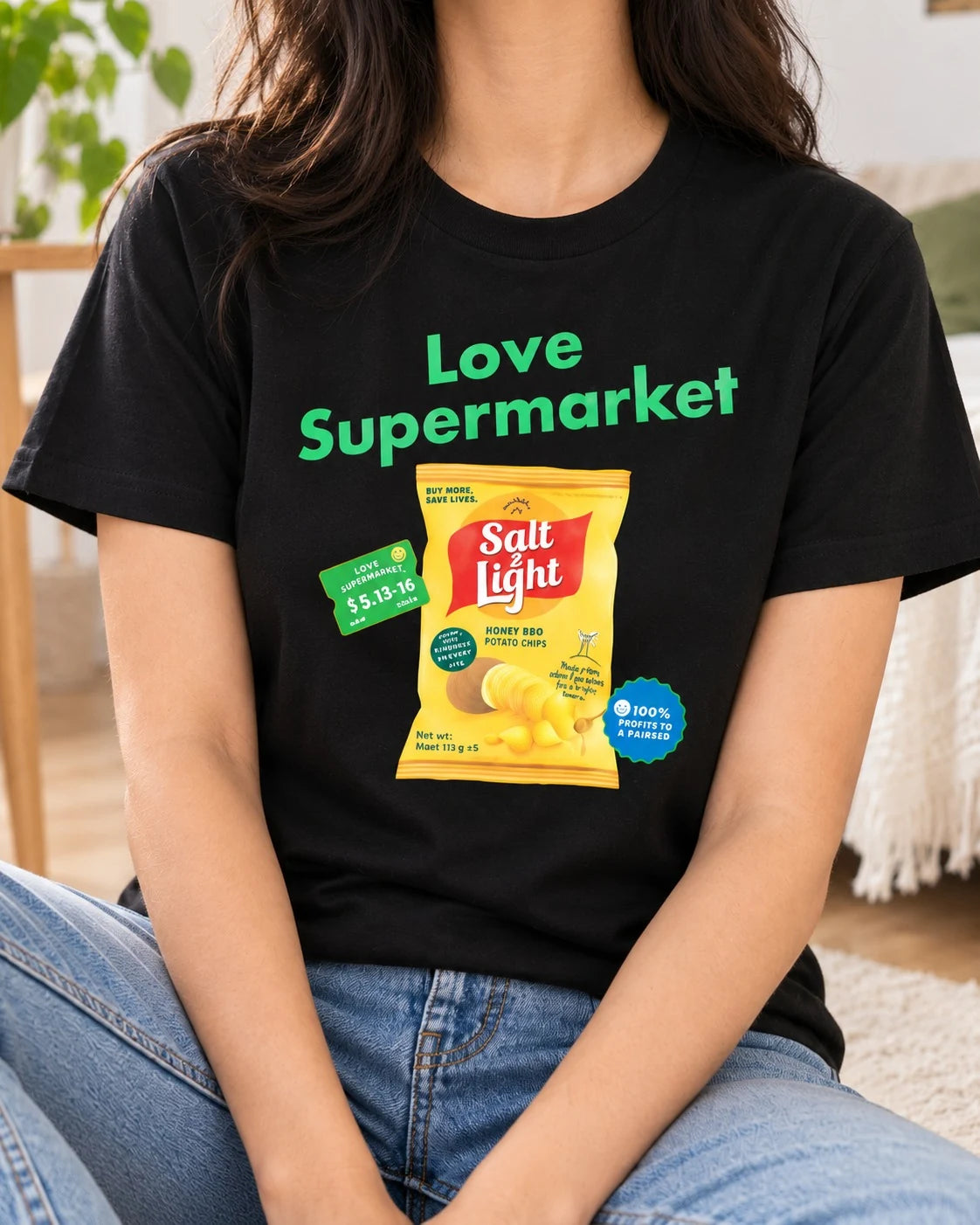 Lifestyle photograph of a woman wearing the black Love Supermarket Salt and Light Potato Chips T-shirt.