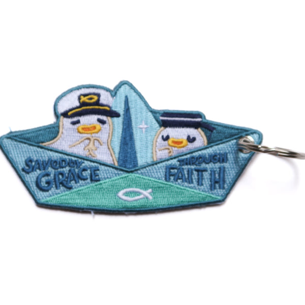 Back view of Christian paper boat keychain with “Saved by Grace Through Faith” text and cute embroidered sailor design.