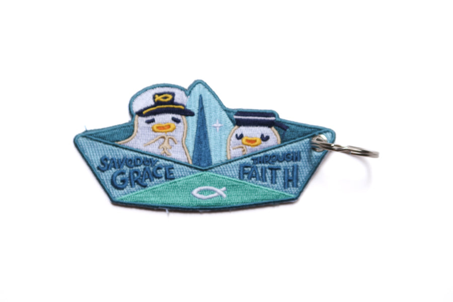 Back view of Christian paper boat keychain with “Saved by Grace Through Faith” text and cute embroidered sailor design.
